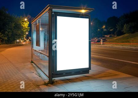 Maquette d'un panneau publicitaire d'arrêt de bus sur Une rue de la ville la nuit. Visionneuse d'affiche extérieure avec des pistes de lumière de voiture en arrière-plan Banque D'Images