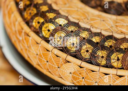 Gros plan d'un panier tissé magnifiquement conçu avec des motifs circulaires complexes dans des tons bruns et or. Le panier présente un mélange de natura Banque D'Images