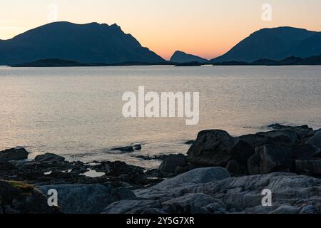 Coucher de soleil chaud nuit nord sur la plage de mer rocheuse avec des montagnes, Lofoten Norvège Banque D'Images