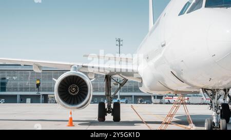 Vue avant de l'avion de passagers - côté droit. Vue rapprochée d'avions blancs sur l'aire de trafic de l'aéroport : fuselage, train d'atterrissage, nacelle de turboréacteur, aile Banque D'Images