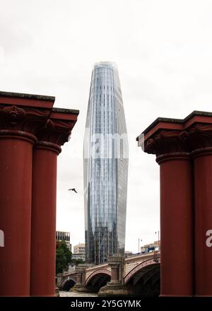 Gratte-ciel à Londres entre 2 vieilles colonnes de pont rouges Banque D'Images