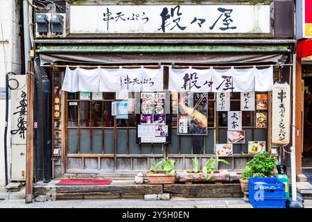 Façade traditionnelle en bois du petit restaurant japonais Izakaya dans le Nishi-Shinjuku, Shinjuku. Entrée porte coulissante, rideau Noren et lanterne. Banque D'Images