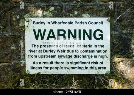 Décharge d'eaux usées dans la rivière Wharfe avertissement à Burley dans Wharfedale Weir près d'Ilkley avec graffiti disant "honte sur vous Yorkshire Water" Royaume-Uni Banque D'Images