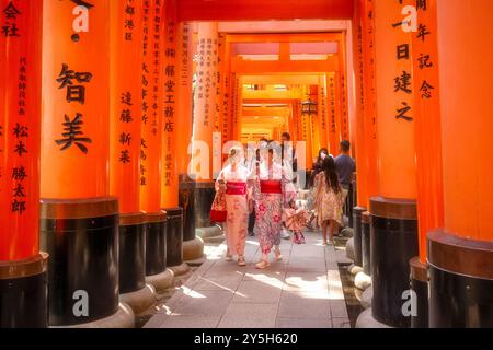 Kyoto, Japon - 19 juin 2024 : deux jeunes femmes portant des kimonos japonais traditionnels, se photographient au sanctuaire Fushimi Inari Taisha et à son th Banque D'Images