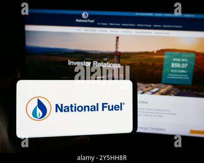 Dans cette illustration photo, une personne tient un smartphone avec le logo de l'entreprise pétrolière et gazière américaine National Fuel Gas Company en face du site Web. Banque D'Images