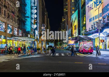 Vue nocturne d'une rue animée de Times Square avec piétons, panneaux d'affichage illuminés et camion de crème glacée rose à New York. ÉTATS-UNIS. Banque D'Images