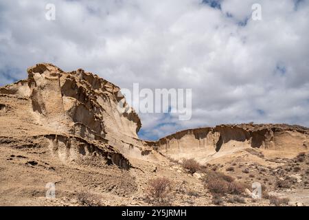Une colline rocheuse avec un ciel nuageux en arrière-plan. Le ciel est principalement bleu avec quelques nuages dispersés partout.dng Banque D'Images