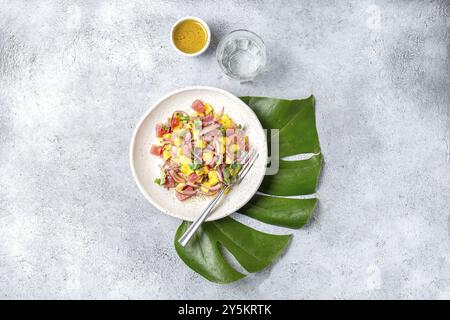 Hawaiian Tropical thon salade de mangue de tahiti sur plaque blanche on tropical monstera leafe Banque D'Images