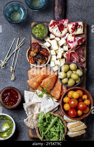 L'antipasto. Set de vin apéritif. Jambon Serrano, saumon fumé, tomates séchées et fromage frais d'olive, du vin à bord. Vue de dessus, l'arrière-plan gris cncrete Banque D'Images