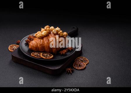 Croissant croustillant sucré avec caramel salé et pop-corn glacé sur un fond texturé foncé Banque D'Images