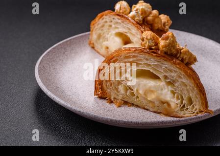 Croissant croustillant sucré avec caramel salé et pop-corn glacé sur un fond texturé foncé Banque D'Images