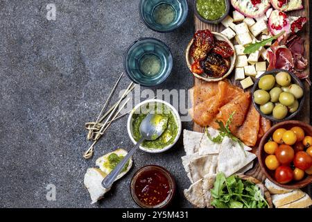 L'antipasto. Set de vin apéritif. Jambon Serrano, saumon fumé, tomates séchées et fromage frais d'olive, du vin à bord. Vue de dessus, l'arrière-plan gris cncrete Banque D'Images