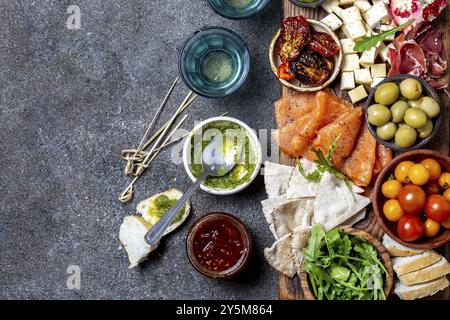 L'antipasto. Set de vin apéritif. Jambon Serrano, saumon fumé, tomates séchées et fromage frais d'olive, du vin à bord. Vue de dessus, l'arrière-plan gris cncrete Banque D'Images