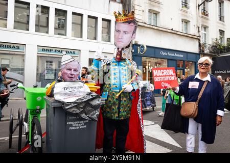 Un manifestant habillé en roi portant un masque du président français Emmanuel Macron met une photo du nouveau premier ministre Michel Barnier à la poubelle lors d'une manifestation contre le gouvernement Macron-Barnier à Paris. Quelques heures avant l'annonce du nouveau gouvernement du premier ministre français Michel Barnier, des milliers de personnes ont manifesté à Paris pour réclamer la destitution du président Emmanuel Macron. L’appel à des manifestations de masse à travers la France est venu du parti de gauche la France insoumise, ainsi que d’écologistes et d’associations étudiantes et féministes. (Photo de Telmo Pinto/SO Banque D'Images