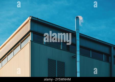 Vapeurs de vapeur provenant de la cheminée de fumée sur un bâtiment industriel, vue à angle bas Banque D'Images