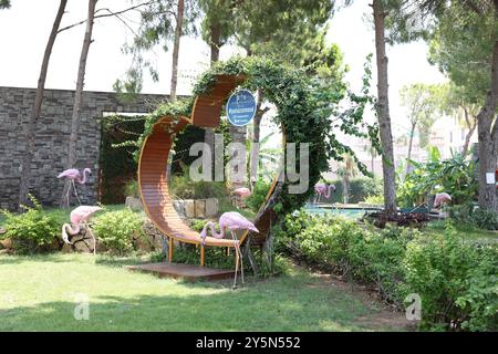 Belek, Turquie - 25 juillet 2024 : banc en bois en forme de coeur et flamants roses décoratifs à l'extérieur Banque D'Images