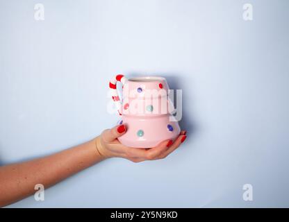 Tasse en forme d'arbre de Noël rose avec des points coloful dans la main des femmes avec copyspace, fond de carte de noël Banque D'Images