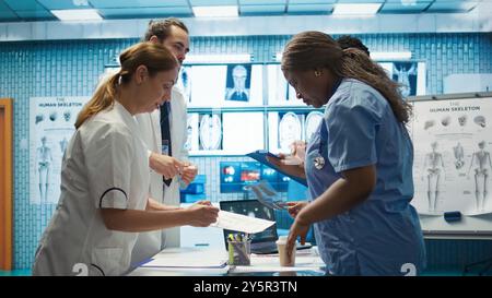 Équipe de spécialistes examinant les résultats de l'ecg lors d'une réunion dans une clinique privée, analysant le système cardiovasculaire sur une radiographie pour la prévention de la maladie. Consultation des scans et des enregistrements. Caméra B. Banque D'Images