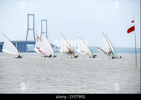 Surabaya. 22 septembre 2024. Cette photo prise le 22 septembre 2024 montre des gens participent à une course traditionnelle de voiliers sur la plage près du pont de Suramadu à Surabaya, Java oriental, Indonésie. Crédit : Sahlan Kurniawan/Xinhua/Alamy Live News Banque D'Images