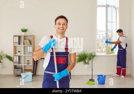 Portrait de travailleur masculin heureux du service de nettoyage de maison tenant la vadrouille et souriant Banque D'Images