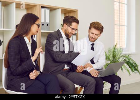 Équipe de gens d'affaires travaillant dans le bureau, en utilisant un ordinateur portable et la lecture de certains documents Banque D'Images