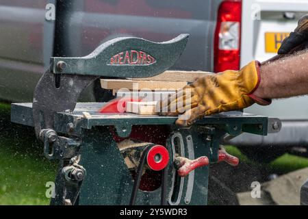 Homme utilisant une scie circulaire à vapeur pour couper de petits morceaux de bois au Newbury Show 2024, Berkshire, Angleterre, Royaume-Uni Banque D'Images