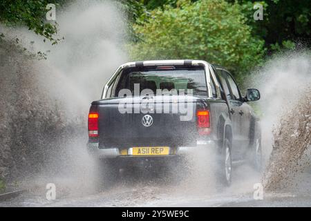 Eton, Windsor, Berkshire, Royaume-Uni. 23 septembre 2024. Un véhicule éclabousse à travers les eaux de crue sur une route de campagne à Eton, Windsor, Berkshire. Le met Office a émis ce matin un avertissement météo Ambre pour la vallée de la Tamise. Crédit : Maureen McLean/Alamy Live News Banque D'Images