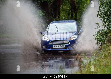 Eton, Windsor, Berkshire, Royaume-Uni. 23 septembre 2024. Un véhicule éclabousse à travers les eaux de crue sur une route de campagne à Eton, Windsor, Berkshire. Le met Office a émis ce matin un avertissement météo Ambre pour la vallée de la Tamise. Crédit : Maureen McLean/Alamy Live News Banque D'Images