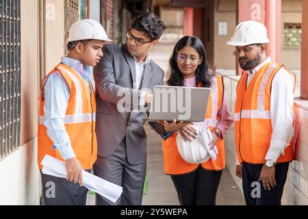Les professionnels occupés sur un chantier de construction, un constructeur immobilier et un gestionnaire de site engagent une conversation intense, discutant de toute urgence de la solution. Banque D'Images