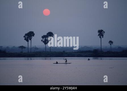 Une magnifique vue de coucher de soleil alors que deux personnes voyagent en bateau, Zaïre, Afrique. Banque D'Images