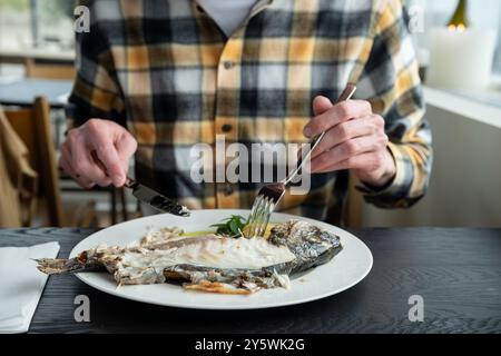 gros plan d'un homme mangeant du poisson cuit au restaurant Banque D'Images
