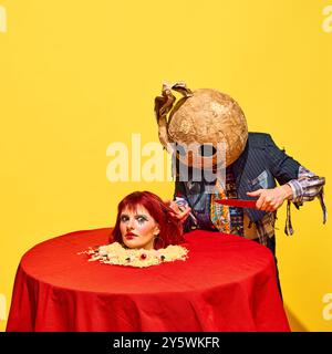 Scène effrayante avec l'homme terrifiant dans le masque pointant avec couteau à la tête de femme sur le plateau de nouilles sur fond jaune vif Banque D'Images