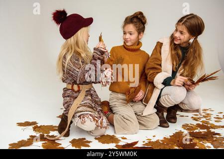 Trois adolescentes ramassant des feuilles d'automne. Banque D'Images