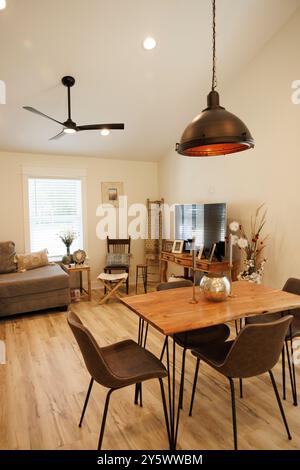 Salon moderne avec une table à manger en bois, des chaises noires et un éclairage suspendu complété par un canapé confortable et télévision, Floride, États-Unis Banque D'Images