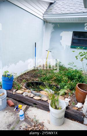 Jardin avec un petit étang entouré de plantes envahies, de seaux et d'outils de jardinage et de vinaigre pour tuer les mauvaises herbes indésirables, Floride, États-Unis Banque D'Images