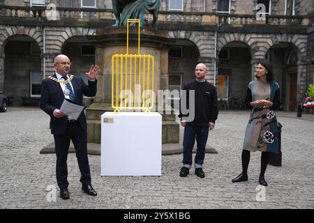 Lord Provost d'Édimbourg Robert Aldridge s'exprimant devant les chambres de la ville d'Édimbourg en tant qu'artiste militant renommé Kostya Benkovich (2e à droite) présente une nouvelle sculpture, la valise, à la ville d'Édimbourg. L'artiste a fui la Russie craignant d'être persécuté en raison de sa position anti-guerre, et la sculpture est inspirée par une femme qui a fui l'Ukraine, qui a déclaré que sa valise était tout ce qu'il lui restait de sa vie antérieure. Date de la photo : lundi 23 septembre 2024. Banque D'Images