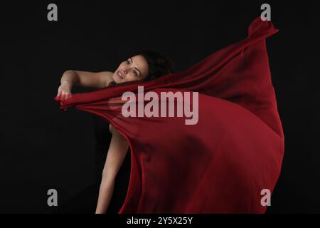 jeune femme latino dansant vêtue de rouge et noir sur fond sombre Banque D'Images