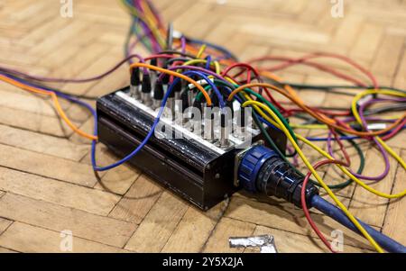 Gros plan d'un appareil électronique complexe avec des fils colorés sur un plancher en bois. Banque D'Images