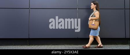 Une jeune femme brune avec de courtes promenades de stature dehors en toute confiance, embrassant l'atmosphère vibrante de son environnement. Banque D'Images