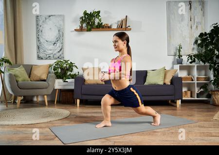 Une jeune femme brune avec une courte stature exercices à la maison, pratiquant des fentes sur un tapis dans son salon confortable rempli de plantes. Banque D'Images