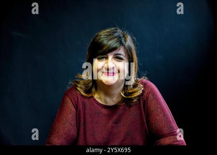 Femme souriante avec les cheveux bruns assis devant un fond noir Banque D'Images