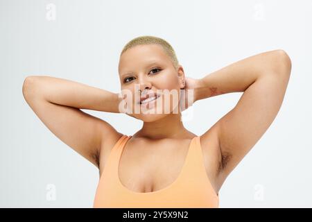 Une jeune femme chauve portant des vêtements lumineux pose gracieusement, rayonnant de confiance et de joie. Banque D'Images