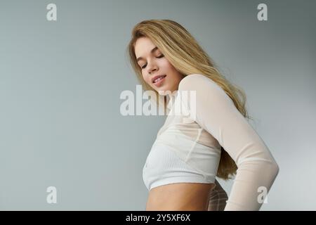 Une jeune femme respire l'élégance avec ses cheveux fluides et sa pose confiante dans un cadre calme. Banque D'Images