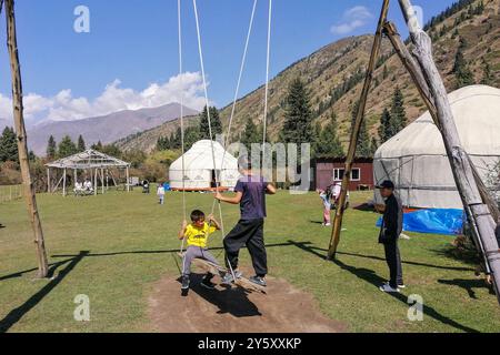 Kirghizistan, vallée de Kyrchyn, enfants sur la balançoire Banque D'Images