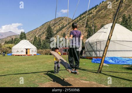 Kirghizistan, vallée de Kyrchyn, enfants sur la balançoire Banque D'Images