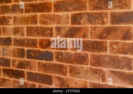 Vue détaillée d'un mur rustique de briques rouges mettant en valeur sa texture naturelle et ses tons terreux. Idéal pour les arrière-plans, les thèmes de construction et l'architecture Banque D'Images