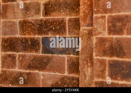 Gros plan détaillé d'un mur rustique de briques brunes présentant sa texture et ses nuances terreuses. Idéal pour l'arrière-plan, la construction ou la conception architecturale c Banque D'Images