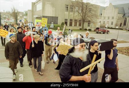 Les manifestants anti-guerre défilent à travers Bloomington, Indiana, portant des signes et des symboles de paix lors d'une manifestation contre l'implication des États-Unis dans les guerres en Afghanistan et en Irak. Les participants tiennent des croix, des signes de paix et des banderoles appelant à la fin de la violence, reflétant l'opposition généralisée aux actions militaires de l'administration Bush. Banque D'Images