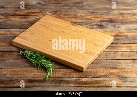 Planche à découper et romarin sur une vieille table en bois. Fond culinaire. Planche à découper en bois vide, espace d'affichage du produit. Banque D'Images