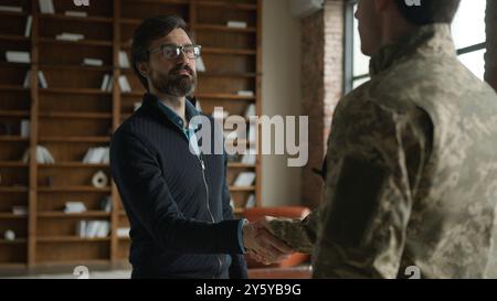 Session de psychothérapie rendez-vous réunion homme caucasien mature homme d'affaires psychologue masculin saluant se serrant la main agent de poignée de main dans le camouflage Banque D'Images